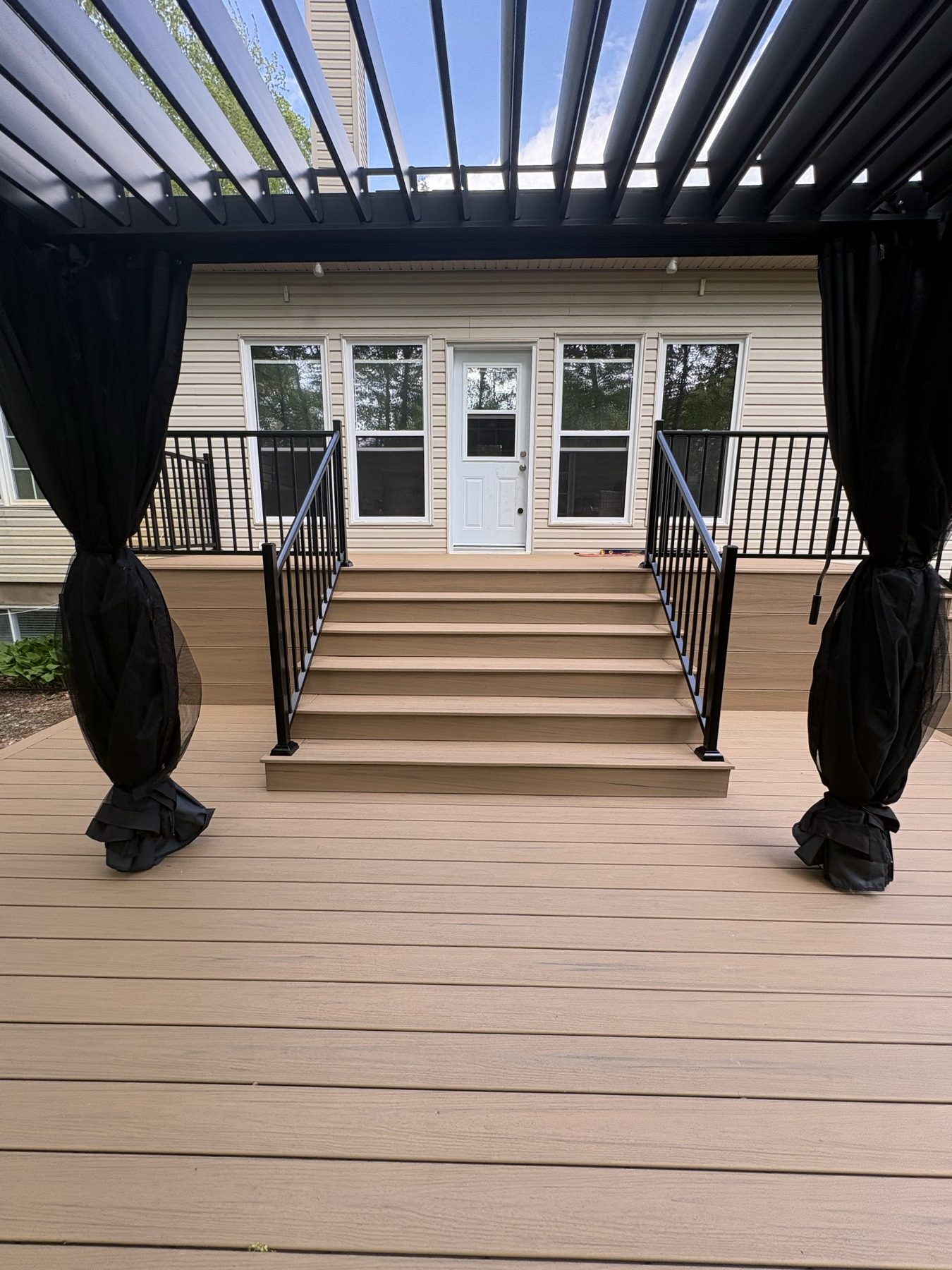 Composite deck and stairs seen through a louvered pergola
